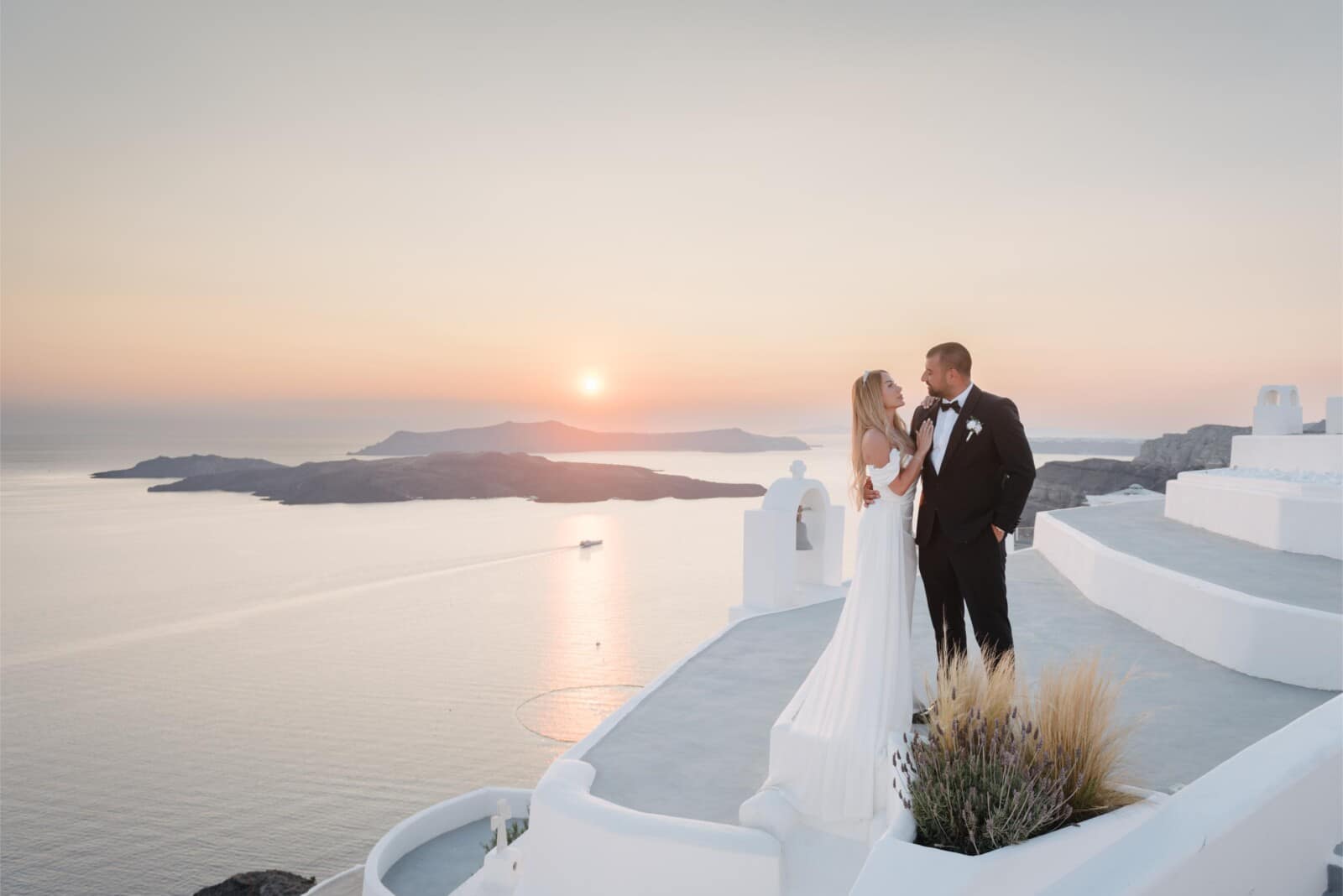 A couple exchanging vows alone at sunset above the Santorini caldera