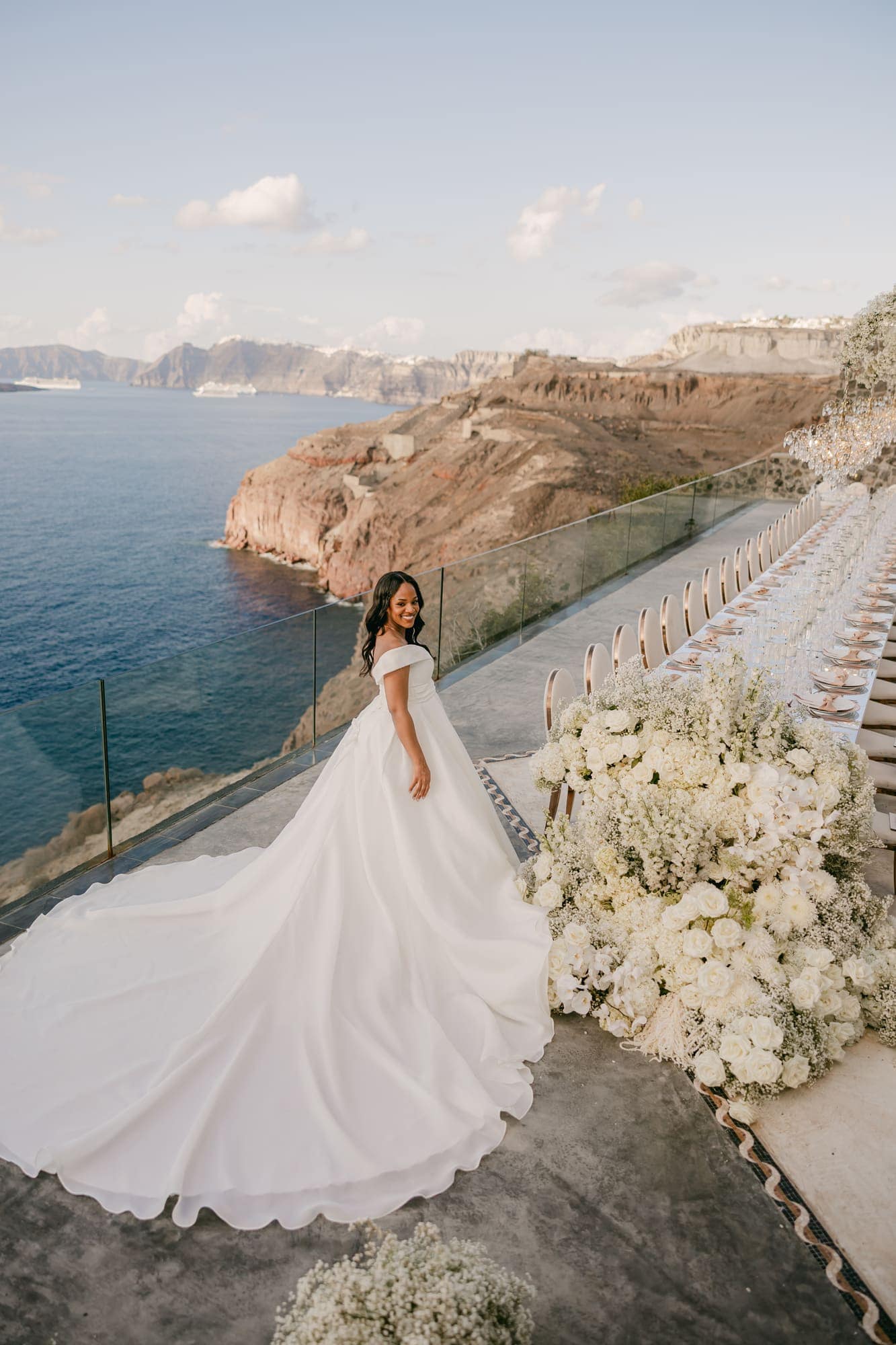 Irlon & Jailleen — the long dinner table set along the cliff edge, Caldera terrace, Santorini