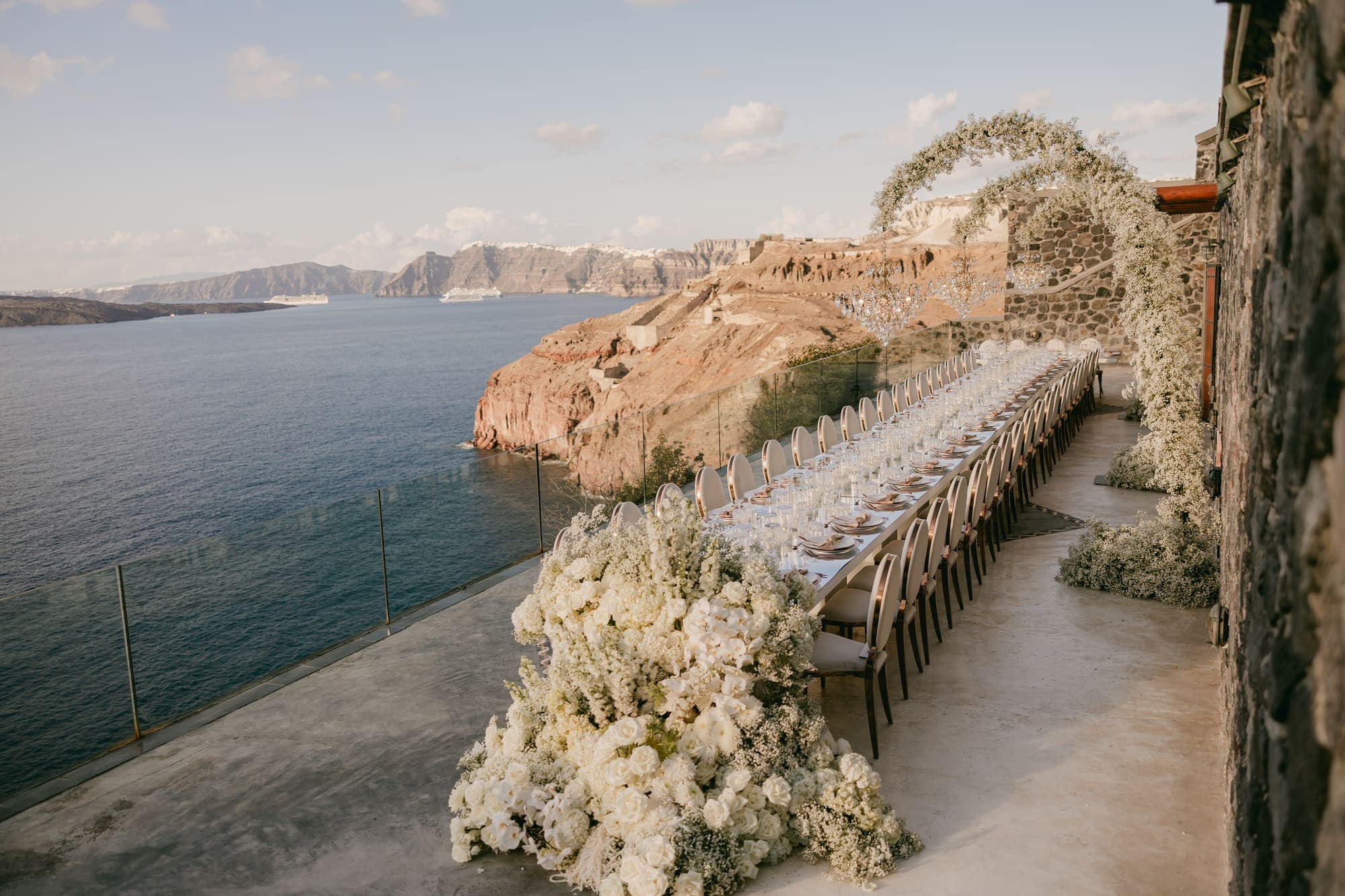 Irlon & Jailleen — the long dinner table set along the cliff edge, Caldera terrace, Santorini