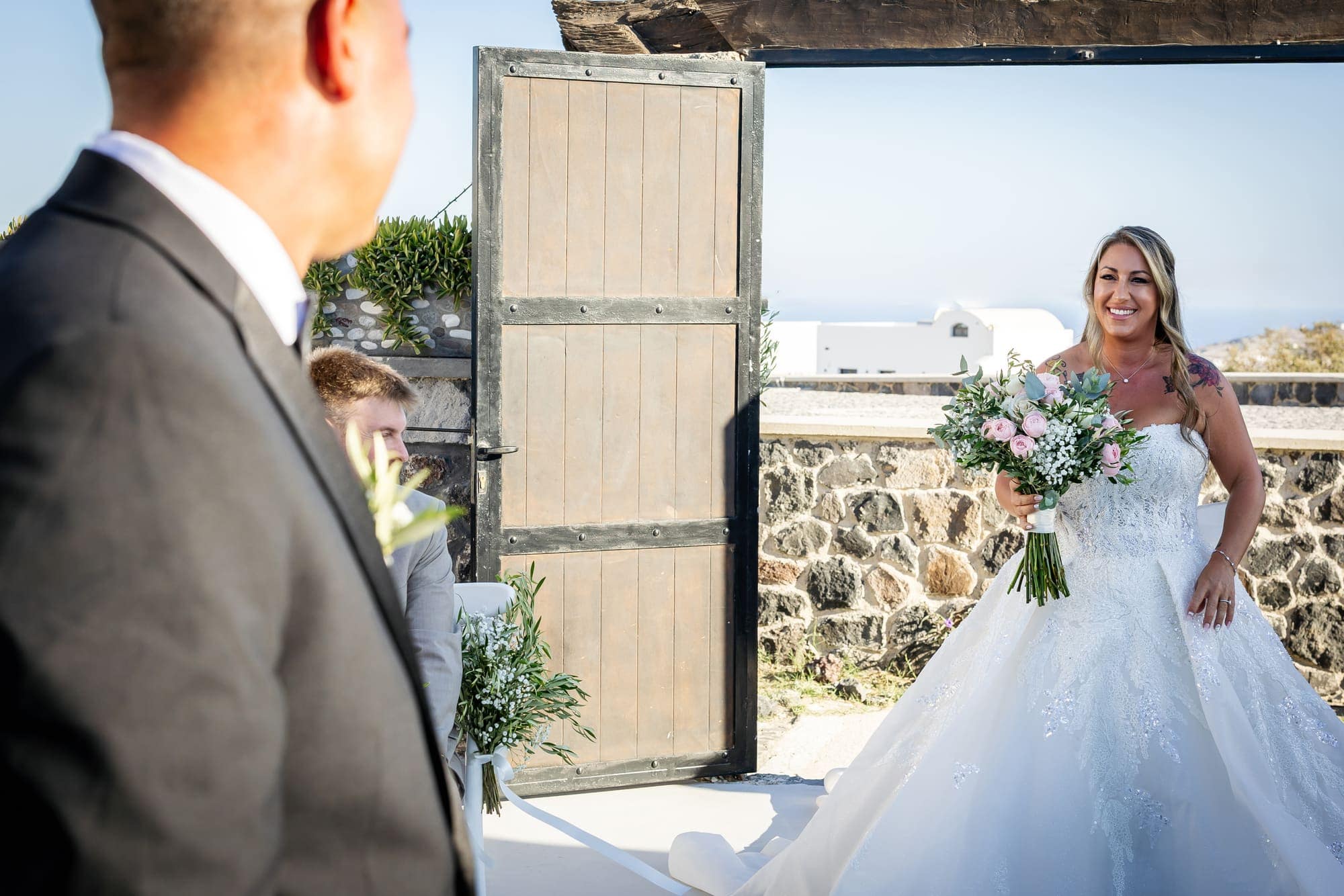 Mary & Chris — the ceremony beneath the crescent floral arch, Windmill venue on the caldera, Santorini