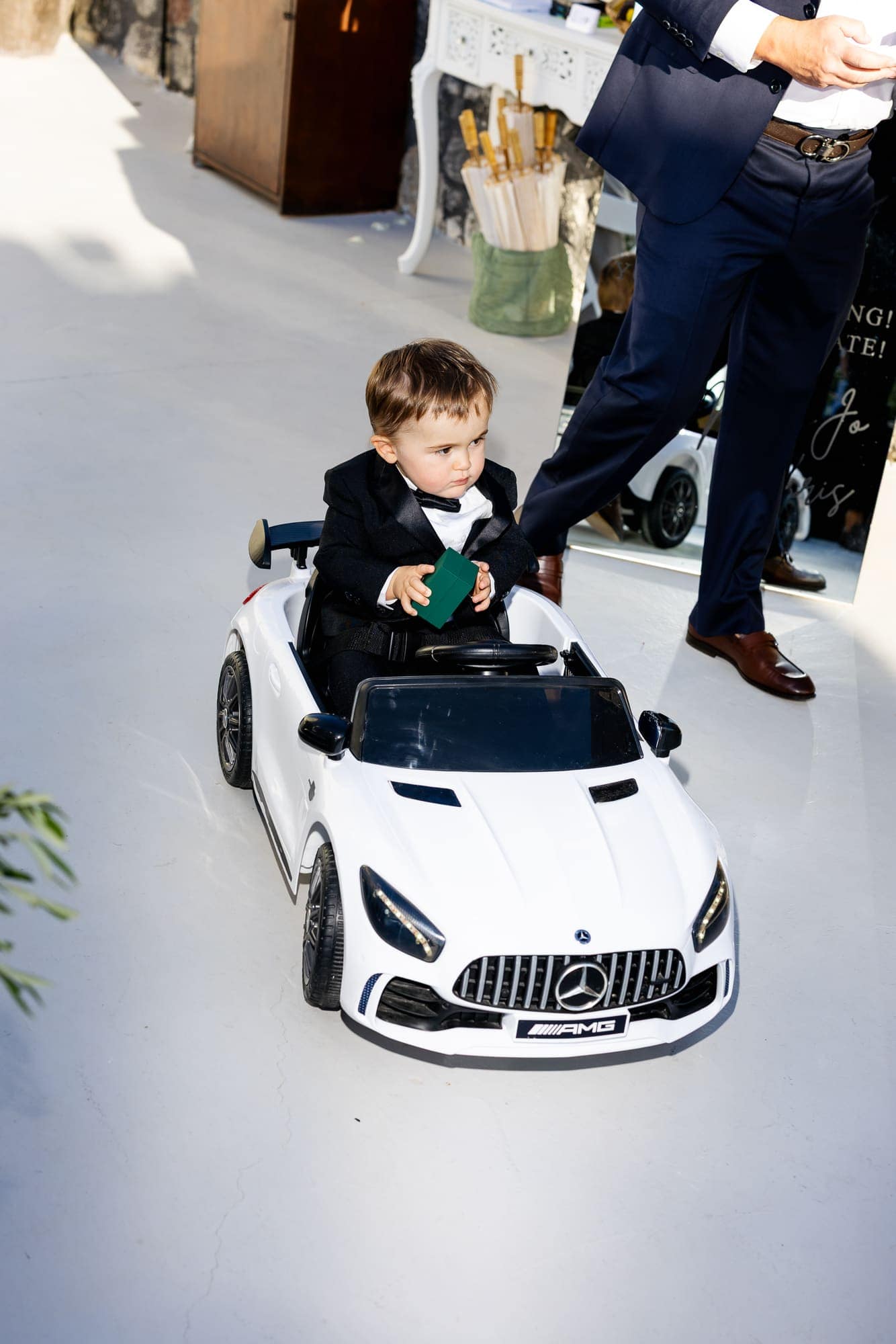 Mary & Chris — the ring bearer arriving in his own miniature convertible, Windmill venue on the caldera, Santorini