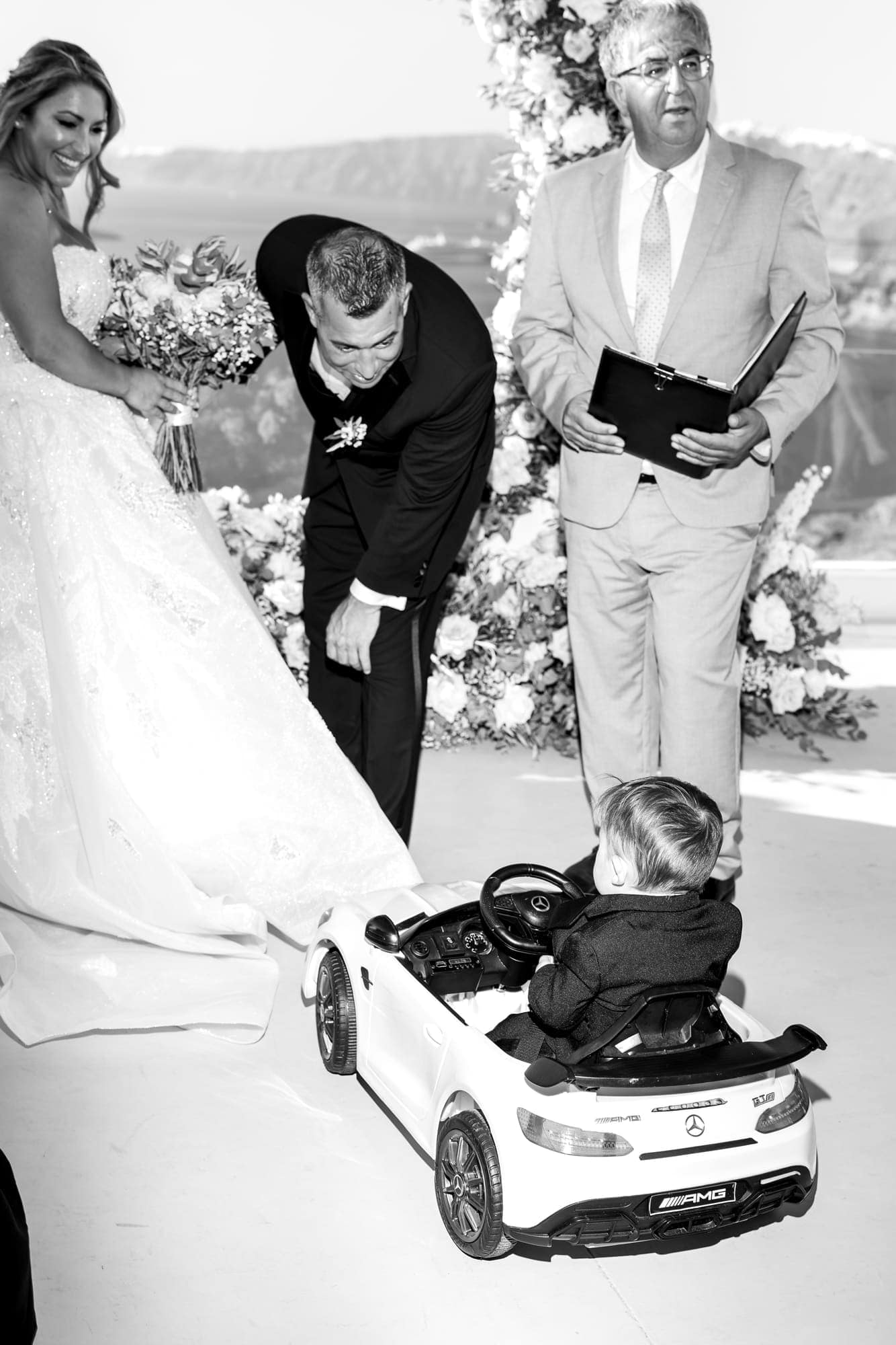 Mary & Chris — the ring bearer arriving in his own miniature convertible, Windmill venue on the caldera, Santorini