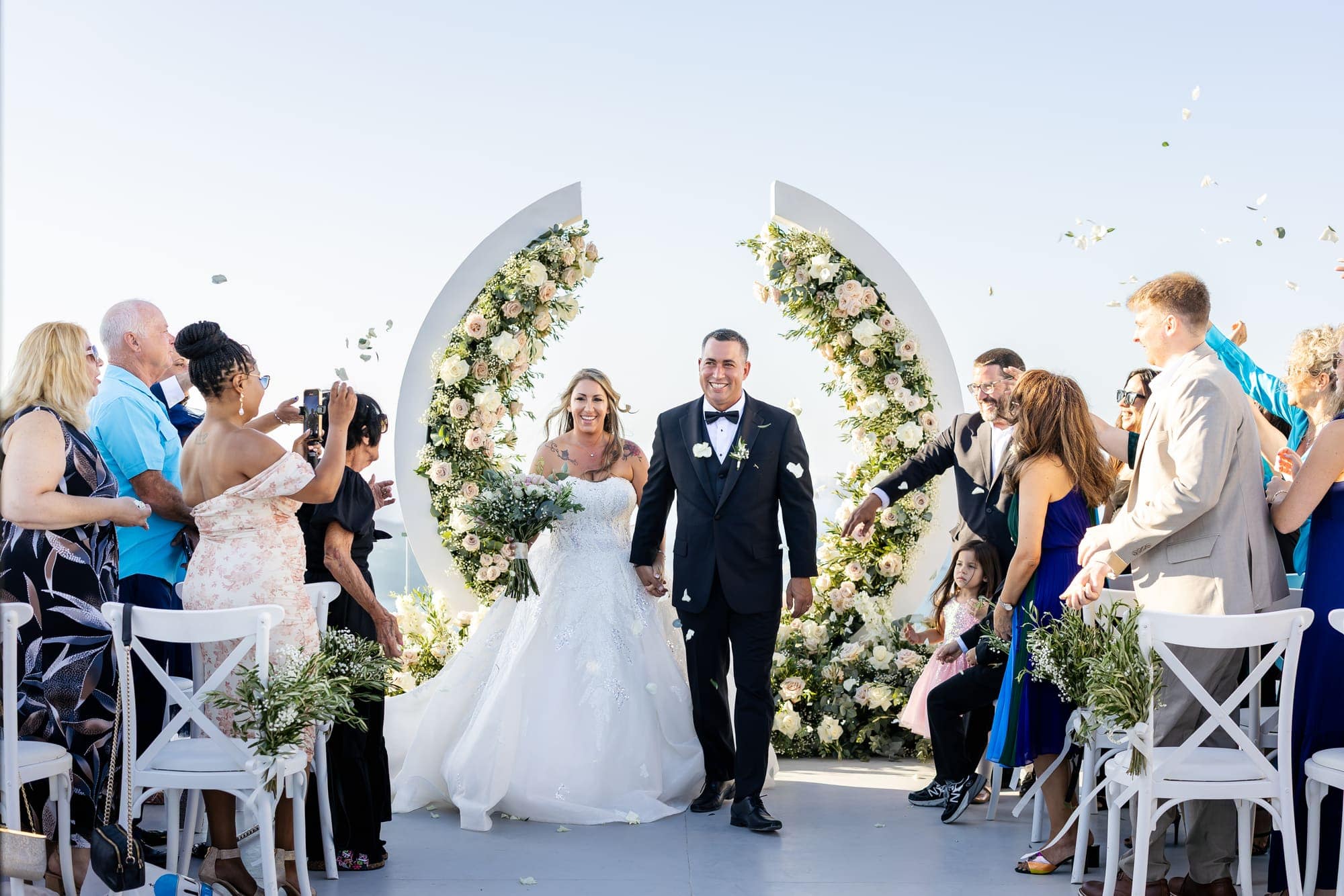 Mary & Chris — the recessional through a shower of confetti, Windmill venue on the caldera, Santorini