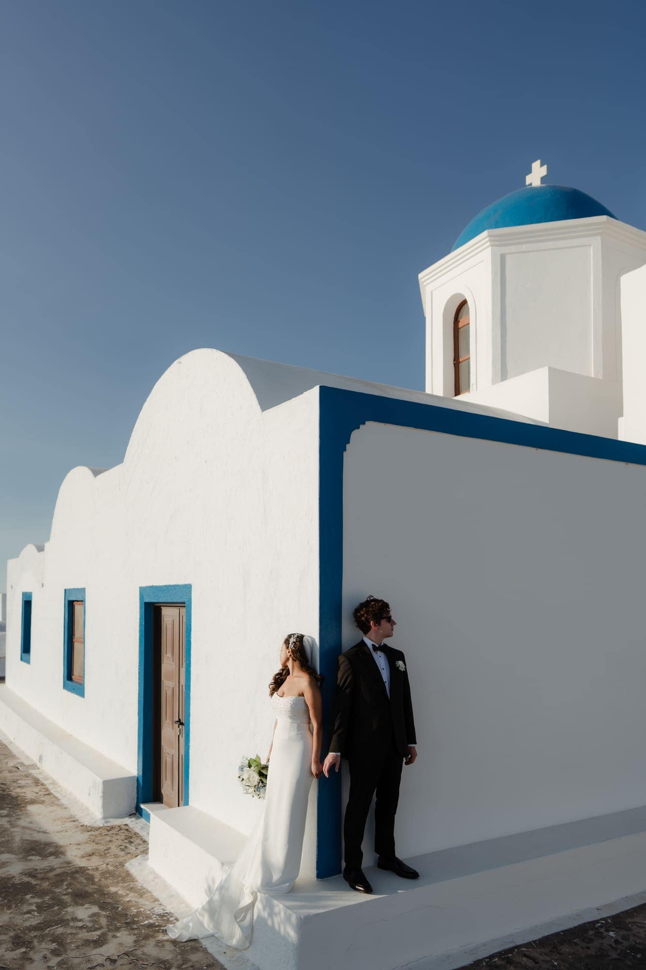 Tina & Kanon — portraits at a small blue-domed chapel, Cliffside terrace, Santorini