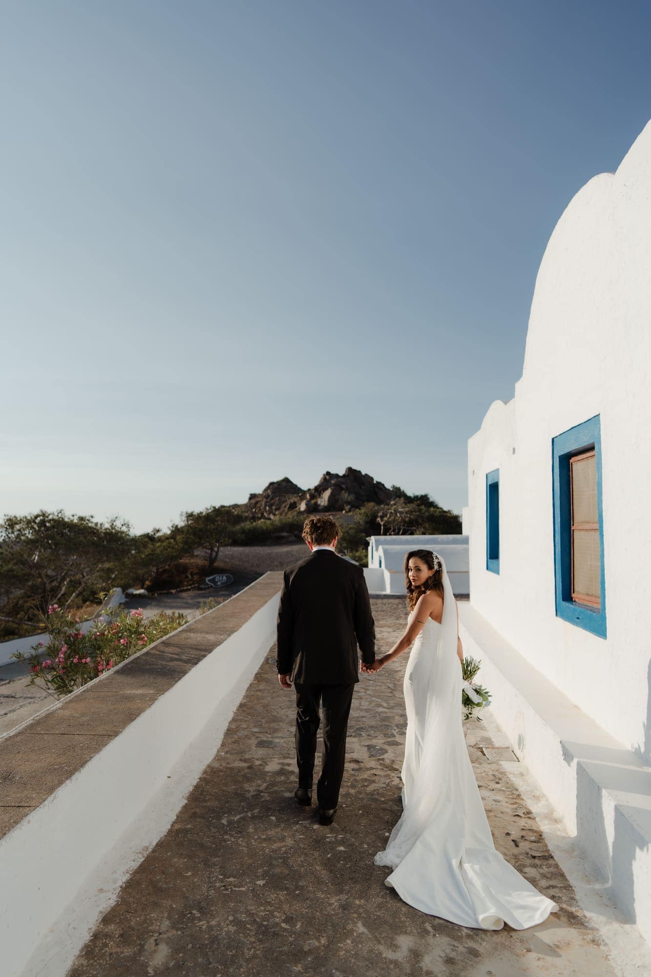 Tina & Kanon — portraits at a small blue-domed chapel, Cliffside terrace, Santorini