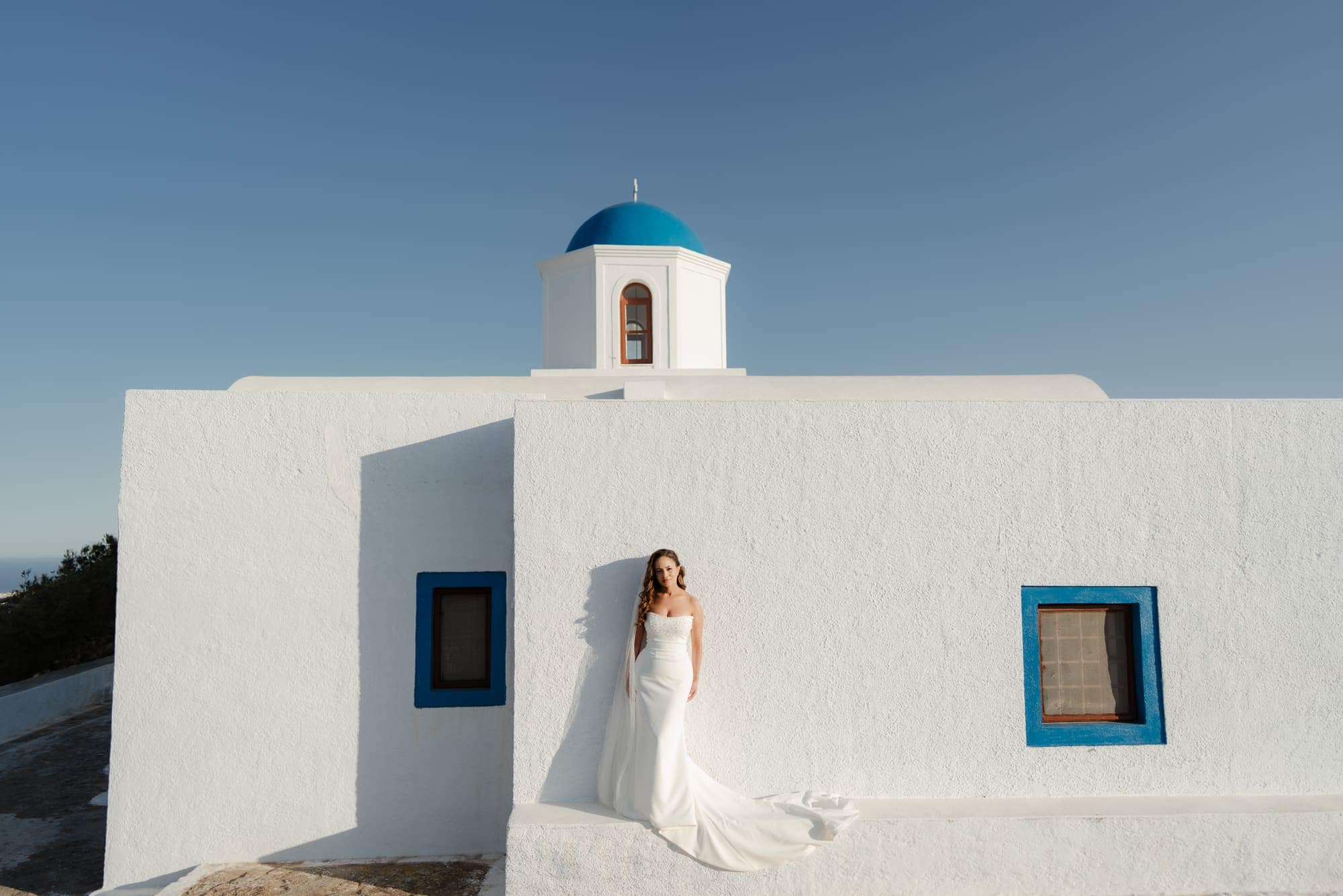 Tina & Kanon — portraits at a small blue-domed chapel, Cliffside terrace, Santorini