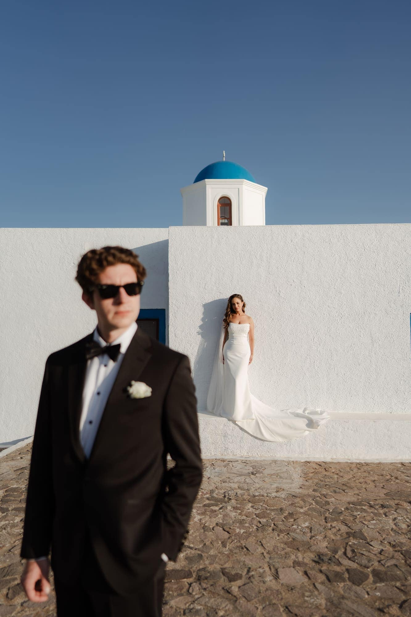 Tina & Kanon — portraits at a small blue-domed chapel, Cliffside terrace, Santorini