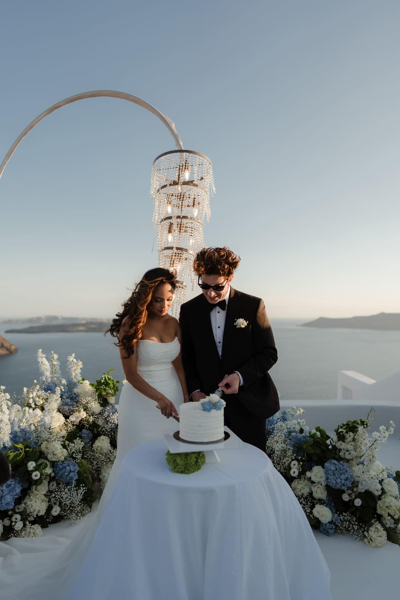 Tina & Kanon — the cake and the violin at sunset, Cliffside terrace, Santorini