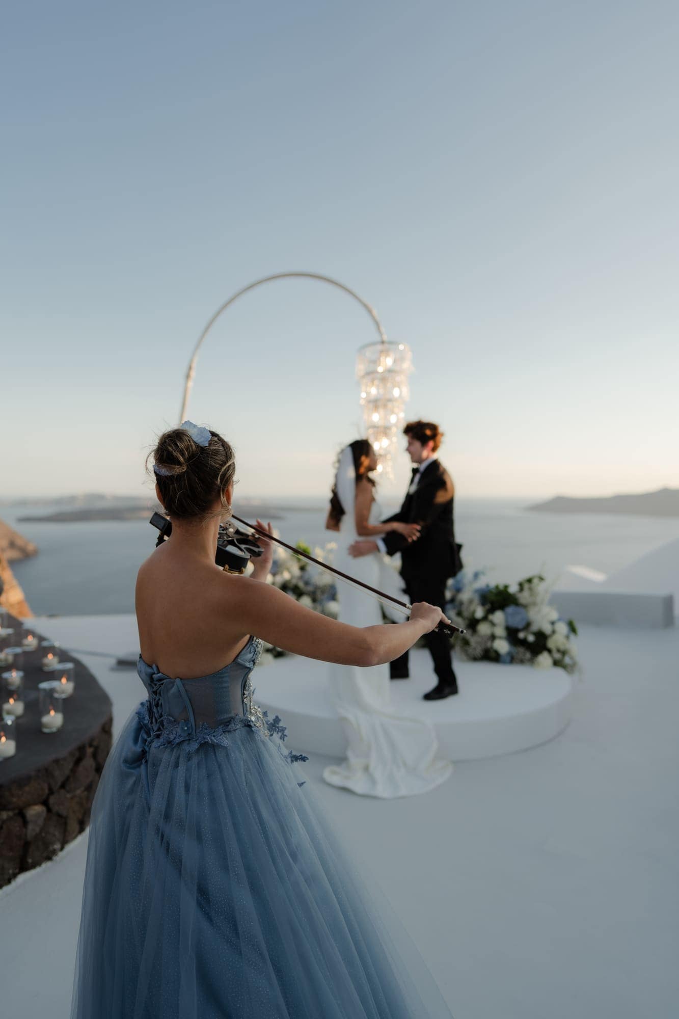Tina & Kanon — the cake and the violin at sunset, Cliffside terrace, Santorini