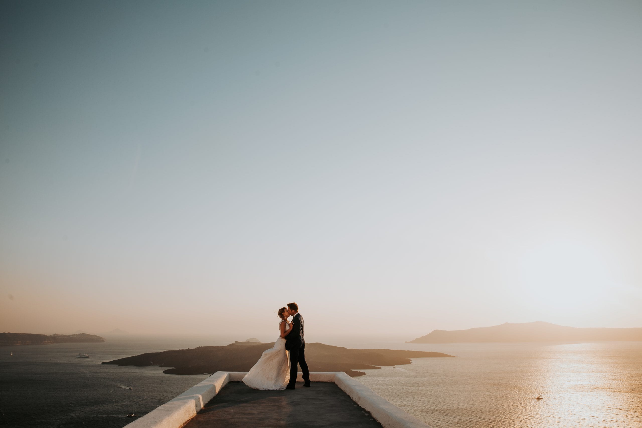 A couple embracing at sunset on a terrace above the Santorini caldera